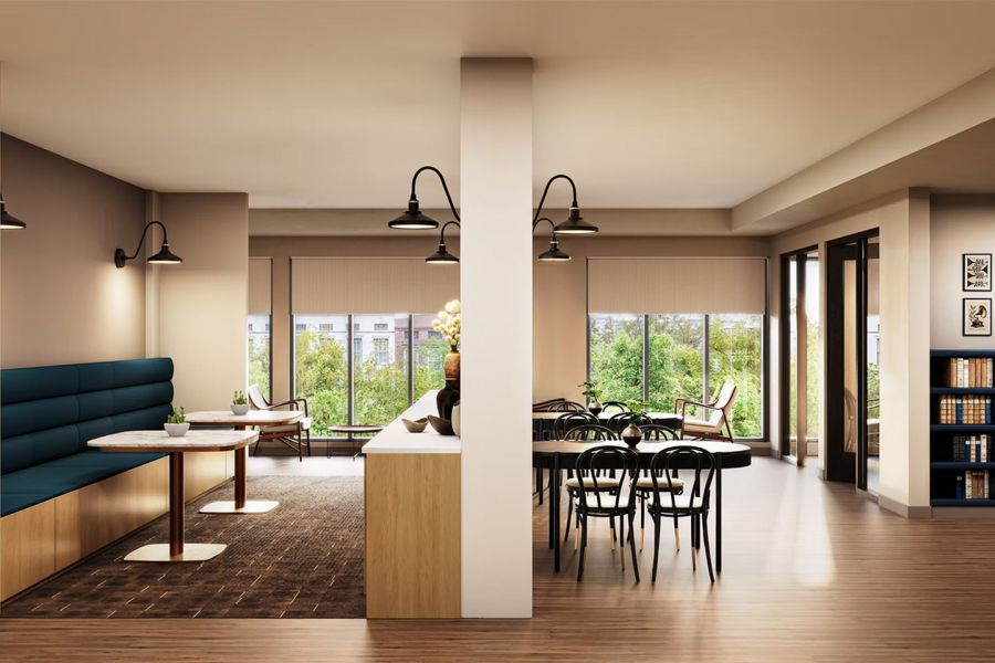 Modern office lounge with booths, tables, shelves, large windows, and greenery visible outside at Bennett Apartments.
